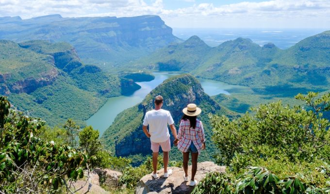 Doi turiști admirând priveliștea spectaculoasă asupra unui canion verde și a unui râu sinuos din Africa de Sud, aproape de Cascada Victoria.