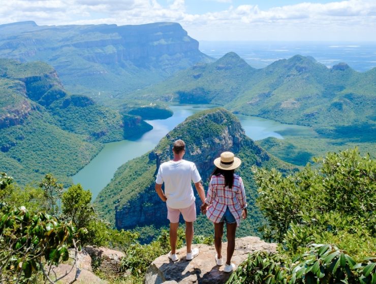 Doi turiști admirând priveliștea spectaculoasă asupra unui canion verde și a unui râu sinuos din Africa de Sud, aproape de Cascada Victoria.
